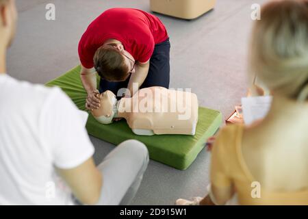 Gruppo di giovani diversi pratica di addestramento di primo soccorso a mano, corso di primo soccorso in CPR manichino. Concetto di abilità di formazione per salvare vite umane, medicina Foto Stock