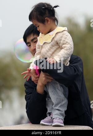 Wuhan, Cina. 02 novembre 2020. Un papà detiene la figlia che è incuriosita dalle bolle in un parco a Wuhan, la capitale della provincia di Hubei, domenica 1 novembre 2020. Il tasso di natalità della Cina è rallentato l'anno scorso al livello più basso dalla formazione della Repubblica popolare cinese nel 1949, aggiungendo preoccupazioni per una sfida a lungo termine per il governo, poiché la società che grava e la forza lavoro in calo hanno fatto pressione su un'economia in rallentamento. Foto di Stephen Shaver/UPI Credit: UPI/Alamy Live News Foto Stock