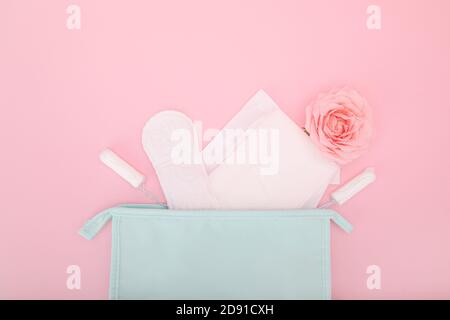 Tamponi sanitari e tamponi che escono da un sacchetto cosmetico su sfondo rosa Foto Stock