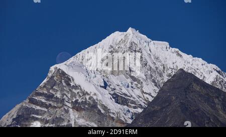 Vista mozzafiato della luna piena che si erge sopra l'impressionante montagna innevata Tengi Raci Tau (picco 6,943 m) vicino a Thame, Khumbu, Himalaya, Nepal. Foto Stock