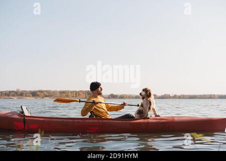 Kayak con cani: Uomo che canottava una barca sul lago con la sua spaniel. Riposo attivo e avventure con gli animali domestici, a cavallo di una canoa con il cane Foto Stock