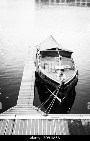 Immagine verticale in scala di grigi di una barca legata a un legno dock Foto Stock