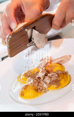 Le mani del cameriere servono il tartufo bianco Alba a fette Ravioli di pasta all'uovo italiana Foto Stock