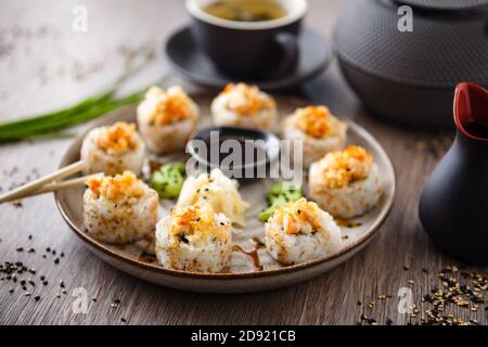 Panini al sushi maki al forno con gamberi e granchio su un piatto con chopsticks, salsa di soia, wasabi e zenzero. Viene servito un primo piano con piatti tradizionali giapponesi a base di pesce Foto Stock