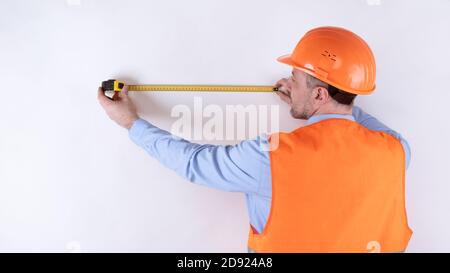 Parete di misurazione per costruttori con metro a nastro in piedi sulla telecamera, studio Foto Stock