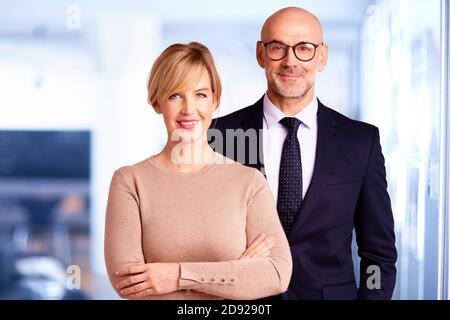 Ritratto della donna d'affari sorridente e uomo d'affari che indossa stile da ufficio mentre si sta in ufficio. Foto Stock