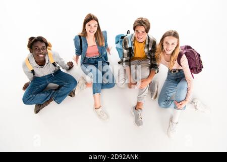 Vista dall'alto di adolescenti multietnici con zaini che sorridono alla fotocamera su sfondo bianco Foto Stock