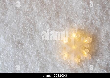Grande decorazione di fiocco di neve brillante su sfondo imitazione di neve con spazio di copia. Decorazione d'umore di Natale. Decorazioni minimali per cartoline o striscioni Foto Stock