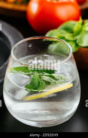 Fresco e luminoso cocktail estivo. Cocktail Mojito con lime, limone e menta in un bicchiere su uno sfondo di pietra alla moda. Mojito limone Foto Stock