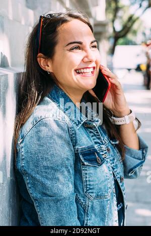 donna felice parla al telefono mentre si scende via Foto Stock