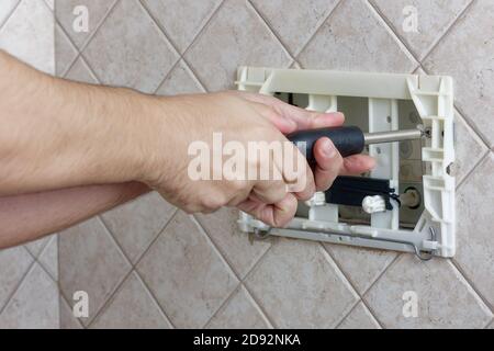 Mani del riparatore svitando una scatola di wc a filo di vite per fissare bagno guardaroba Foto Stock