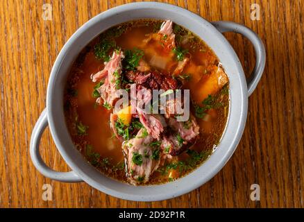 Zuppa con carne di costolette di maiale affumicate, verdure ed erbe - vista dall'alto Foto Stock