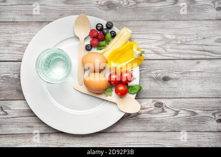 Concetto di dieta a digiuno a intervalli rappresentato con un piatto e prodotti Foto Stock