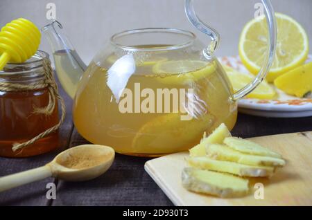 mettere la curcuma in una teiera per fare una bevanda sana. Teiera di tè allo zenzero con miele e limone su tavolo di legno. Tazza di tè allo zenzero con miele e limone Foto Stock