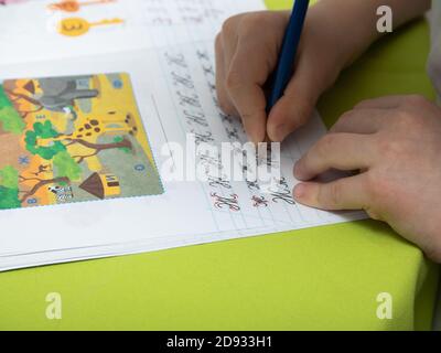 Mosca/Russia - 04.01.2020 : UN ragazzo fa i suoi compiti. Apprendimento a distanza in quarantena. Libri di testo, taccuini sono sul tavolo. Mano del bambino con un penc Foto Stock