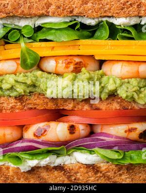 Club sandwich con gamberi, pomodori, formaggio, cipolle, avocado. Foto full frame creativa. Foto Stock