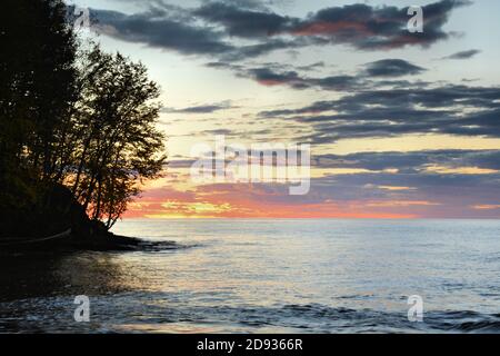 Un tramonto brillante fa addensare le nuvole sulle acque tranquille Del Lago superiore Foto Stock