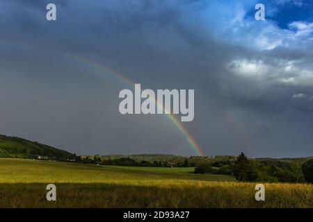 Doppio arcobaleno in campagna. Bella intensa arcobaleno colori in pioggia day.Weather forecast.Fall paesaggio rurale con arcobaleno su scuro drammatico Sto Foto Stock