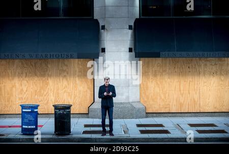 Washington DC, USA, 2 novembre 2020, UN uomo che guarda il suo telefono mentre di fronte ad un imbarco su storefront. Washington DC è stato imbarcato in preparazione di possibili elezioni 2020 rivolte correlate il 3 novembre a Washington DC, USA, Credit: Yuriy Zahvoyskyy / Alamy Live News Foto Stock