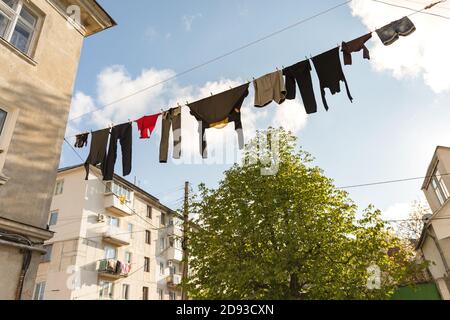 Il lino puro è asciugato sulla strada. Vestiti appesi ad asciugare sulla corda. Lavanderia appesa tra le case Foto Stock