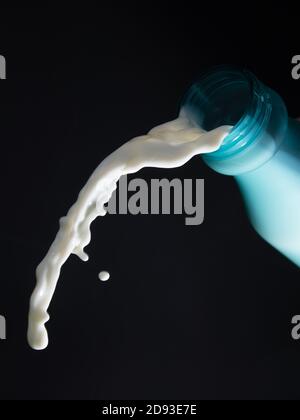 versamento di latte dal flacone o schizzi di liquido bianco isolati sfondo nero Foto Stock