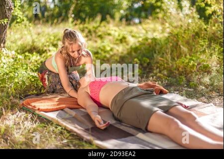 L'addestratore di massaggio applica le sue abilità di massaggio sul suo cliente sull'erba. Foto Stock