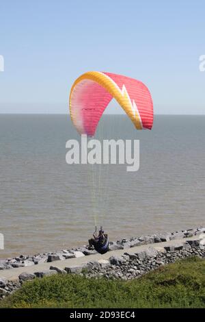 Parapendio contro un cielo blu luminoso sulla costa dell'Essex Foto Stock