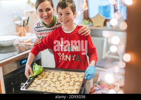 Famiglia cottura dei biscotti di Natale in cucina portando foglio con l'impasto Foto Stock