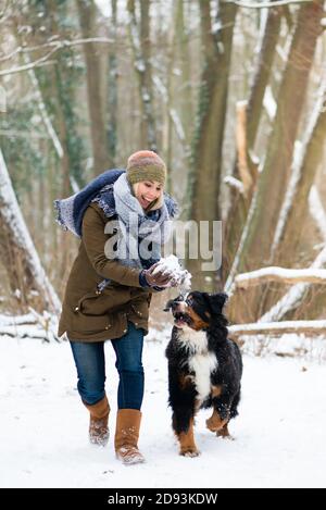 Donna che gioca con il suo cane nella neve Foto Stock