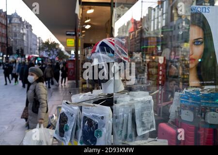 Mentre il Regno Unito reagisce all'annuncio del primo ministro Boris Johnson di Lockdown 2 durante la seconda ondata della pandemia di Coronavirus, schermi facciali e maschere sono in vendita in una vetrina di un rivenditore su Oxford Street, il 2 novembre 2020, a Londra, Inghilterra. A partire da mezzanotte di giovedì, tutti i negozi, i bar, i ristoranti e le altre piccole aziende non essenziali dovranno chiudere, secondo le restrizioni del Covid del governo - e per un minimo di 4 settimane nel periodo che va da Natale a Natale. Foto Stock