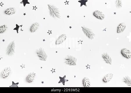 Sfondo bianco di Natale o Capodanno con pini e confetti a forma di stella argentata. Vista dall'alto. Disposizione piatta. Foto Stock