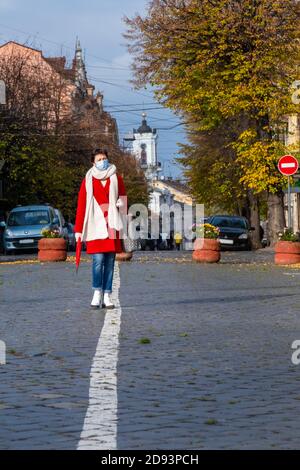 Donna di mezza età con maschera medica protettiva sul viso Passeggiate sulla strada in città durante il periodo Covid-19 Foto Stock