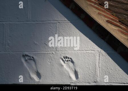 Due impressioni di piedi nel rendering su una parete della casa. Forse dei proprietari. Foto Stock