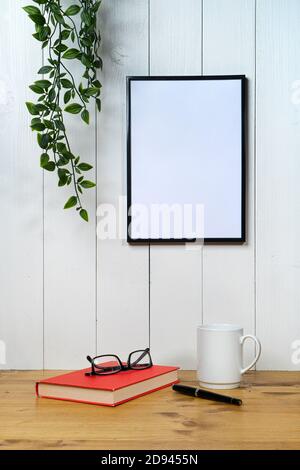 una cornice nera vuota e un'edera su un bianco legno di fondo Foto Stock