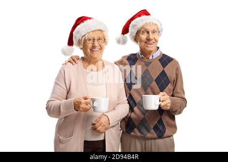 Coppia anziana che tiene tazze da tè e indossa cappelli babbo natale isolato su sfondo bianco Foto Stock
