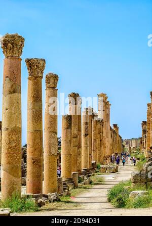 I turisti passeggiano lungo l'antica via colonnata del Cardo Maximus Jerash nel nord della Giordania Foto Stock