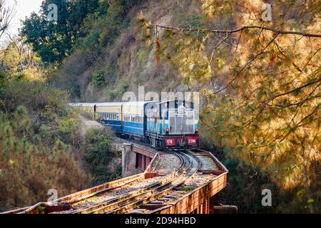 Un treno diesel indiano in avvicinamento sulle piste ferroviarie su un ponte attraverso una gola a Himachal Pradesh, India settentrionale Foto Stock