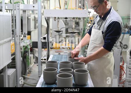 (201103) -- DEHUA, 3 novembre 2020 (Xinhua) -- UN lavoratore esamina le basi di terra per essere fatte in pentole di pianta su una linea di produzione automatizzata di una fabbrica di porcellana nella contea di Dehua, Quanzhou, la provincia di Fujian della Cina sudorientale, 21 ottobre 2020. Un importante centro di produzione di porcellana, Dehua, nella provincia di Fujian, nella Cina sudorientale, produce porcellane d'esportazione sin dalla dinastia Song (960-1279 d.C.). La porcellana bianca semplice qui lavorata fu successivamente soprannominata 'Blanc de Chine (Bianco dalla Cina)' dai francesi e guadagnò fama mondiale. Come uno dei forni tradizionali del drago con la struttura lunga, sottile e leggermente inclinata Foto Stock