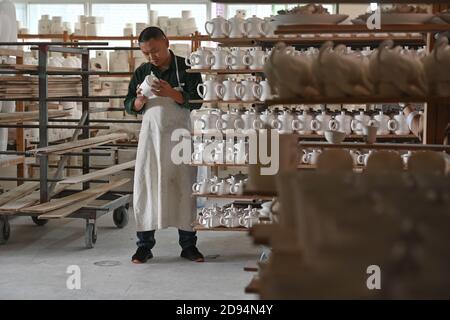 (201103) -- DEHUA, 3 novembre 2020 (Xinhua) -- Artisan Xu Jinbao esamina il teaware di porcellana bianca nella contea di Dehua, Quanzhou, provincia del Fujian della Cina sudorientale, 21 ottobre 2020. Un importante centro di produzione di porcellana, Dehua, nella provincia di Fujian, nella Cina sudorientale, produce porcellane d'esportazione sin dalla dinastia Song (960-1279 d.C.). La porcellana bianca semplice qui lavorata fu successivamente soprannominata 'Blanc de Chine (Bianco dalla Cina)' dai francesi e guadagnò fama mondiale. Come uno dei forni tradizionali del drago con le strutture lunghe, sottili e leggermente inclinate, l'unico forno antico rimanente in Dehua è il Yueji Ki Foto Stock