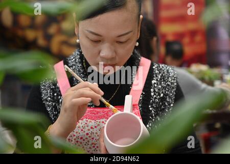 (201103) -- DEHUA, 3 novembre 2020 (Xinhua) -- UN operaio colora una tazza in una fabbrica di porcellana nella contea di Dehua, Quanzhou, provincia del Fujian della Cina sudorientale, 21 ottobre 2020. Un importante centro di produzione di porcellana, Dehua, nella provincia di Fujian, nella Cina sudorientale, produce porcellane d'esportazione sin dalla dinastia Song (960-1279 d.C.). La porcellana bianca semplice qui lavorata fu successivamente soprannominata 'Blanc de Chine (Bianco dalla Cina)' dai francesi e guadagnò fama mondiale. Come uno dei forni tradizionali del drago con le strutture lunghe, sottili e leggermente inclinate, l'unico forno antico rimanente a Dehua è il forno Yueji, wh Foto Stock