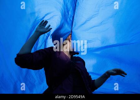 Un attivista che indossa una maschera facciale è visto all'interno del panno blu durante la dimostrazione.durante la terza ribellione internazionale, il movimento della ribellione estinzione ha bloccato Gran Vía Street a Madrid per protestare contro le conseguenze dell'aumento del livello del mare. Il movimento, che porta un panno blu di 150 metri quadrati da piazza Callao a piazza Spagna, attraversa via Gran Vía per rendere visibile il crescente numero di persone colpite dall'aumento del livello del mare, causato dal cambiamento climatico. Questo atto, sotto il nome di 'noi affondare' ha rappresentato l'enorme numero di morti a causa dell'aumento del livello del mare. Foto Stock