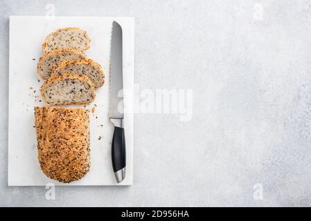 Pane multigrein affettato su una tavola di marmo. Sfondo grigio in cemento. Spazio di copia della vista superiore per testo o disegno. Pane appena sfornato Foto Stock