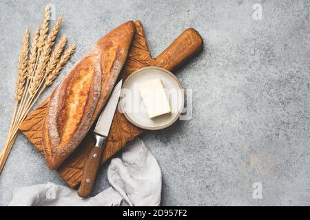 Pane fresco baguette e burro su fondo di cemento. Spazio di copia della vista superiore per il testo Foto Stock