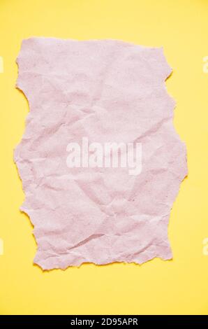 Un pezzo di carta artigianale con bordi irregolari giace su uno sfondo giallo. La vista dall'alto. Bock up Foto Stock