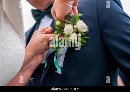 boutonniere dello sposo con fiori bianchi e verdi Foto Stock