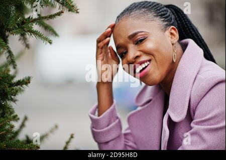 Giovane elegante bella donna afroamericana in strada vicino ai pini, indossando abiti di moda. Foto Stock