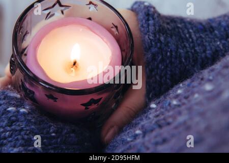 Ragazza in morbido caldo blu scuro maglia maglione tiene in mani che bruciano candela. Candela di Natale. In attesa della vacanza Foto Stock