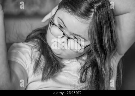 Giovane adolescente femminile con la sindrome di Downs spazzolando i suoi capelli all'interno, Northampton, Inghilterra, UK. Foto Stock