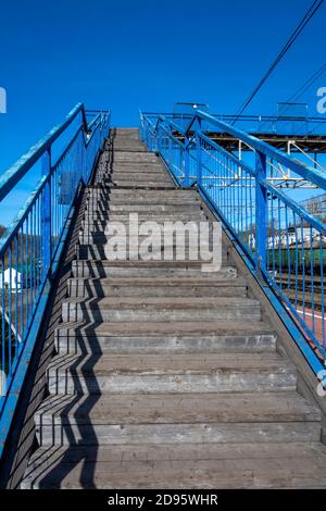 Scalinata per l'attraversamento pedonale delle strade di accesso alla stazione ferroviaria, contro il cielo senza nuvole Foto Stock