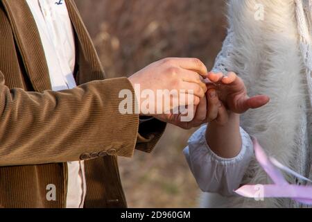 Un closeup di un uomo che mette un anello di aggancio sopra la sua ragazza Foto Stock